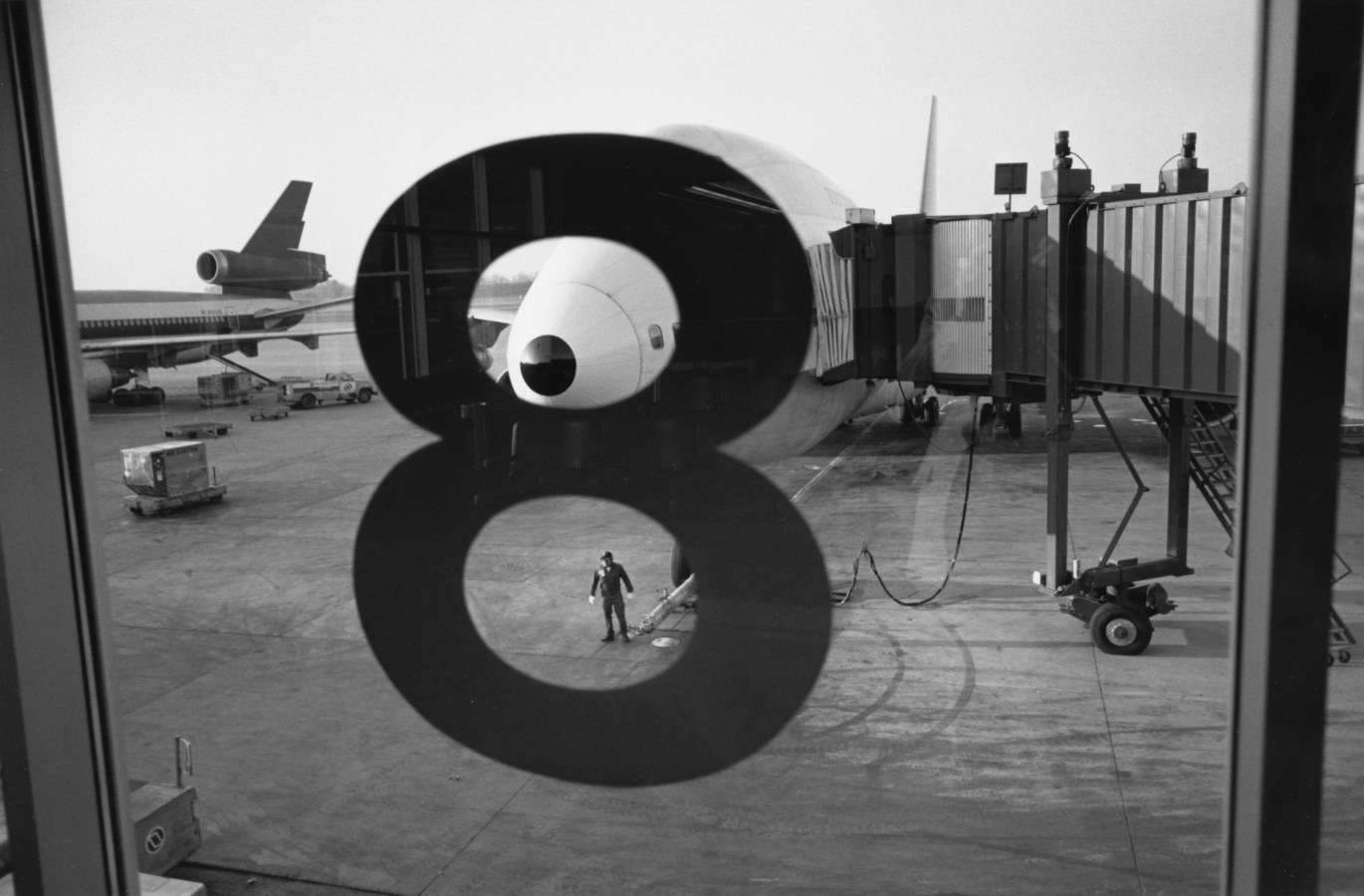 Black and white photograph looking out an airport window with the number 8 on it