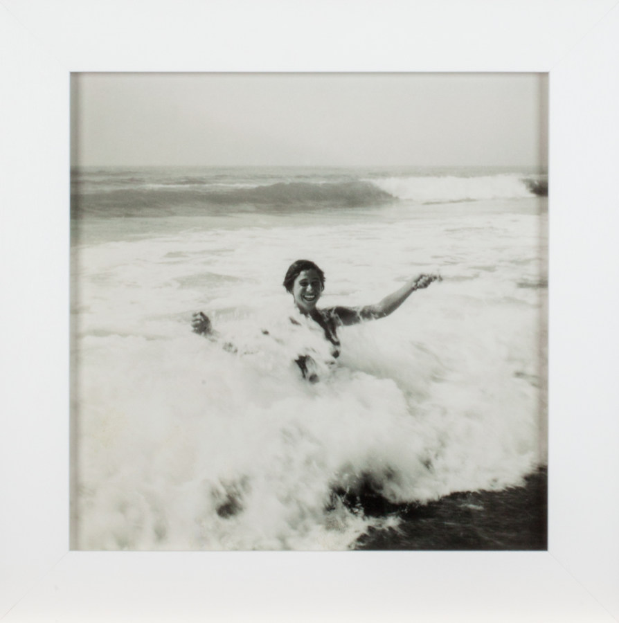 A framed square black and white photograph of a woman in the ocean