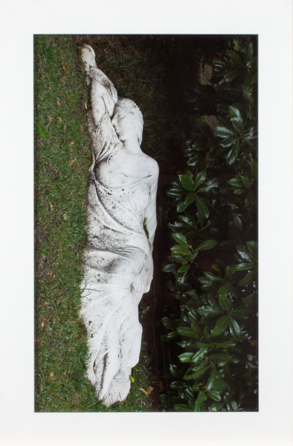 A framed photograph of a sculpture of a woman lying on her side, turned 90 degrees clockwise