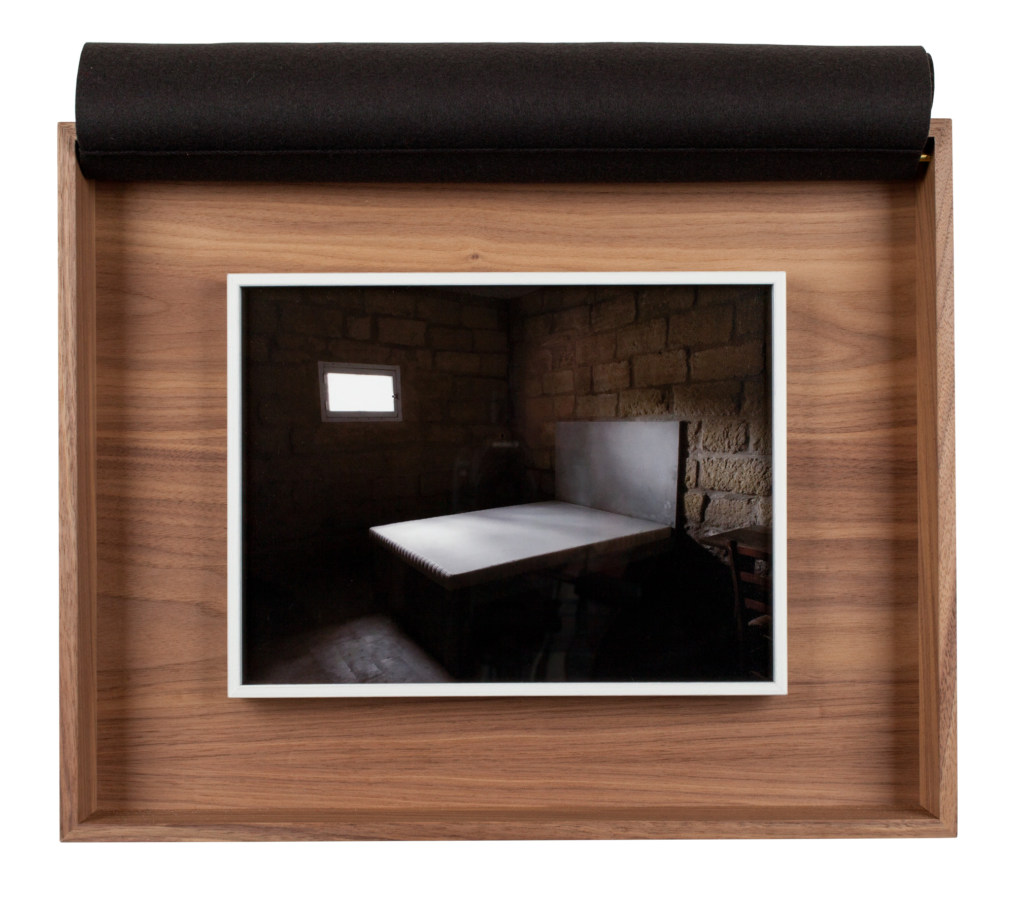 A framed photograph of a concrete bed, inside a wooden box