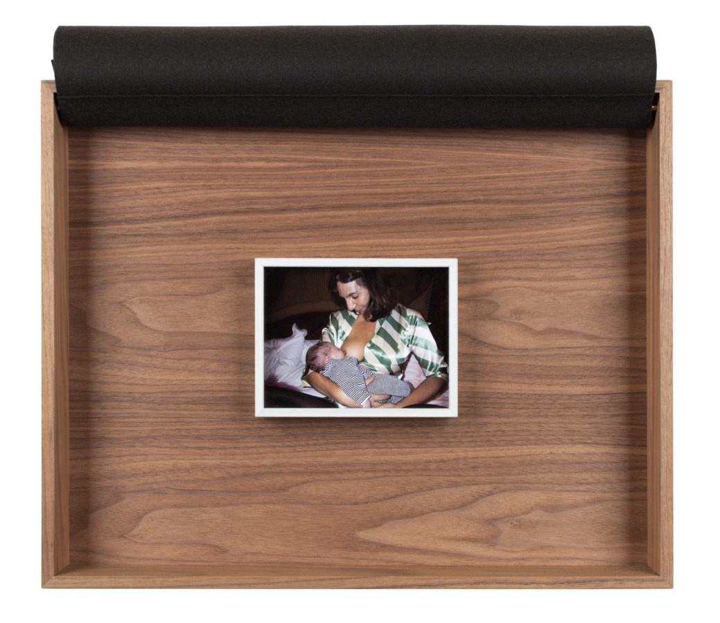A framed photograph of the artist holding a child to her breast, inside a wooden box