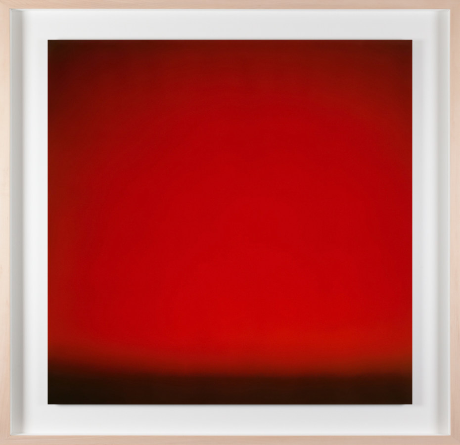 A framed photograph of a red color field, with black line at bottom