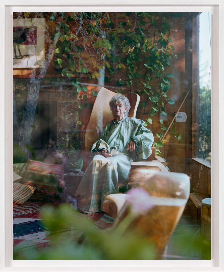 A framed photograph of an elderly woman as seen through a window