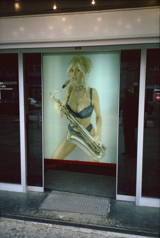 A photograph of an advertisement of a woman in lingerie playing a saxophone, behind sliding doors.