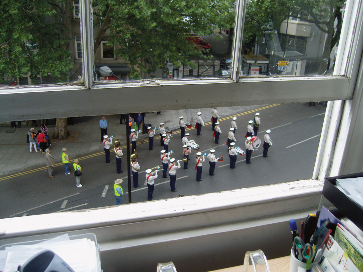 A photograph of a marching band, as seen through a barely-open window
