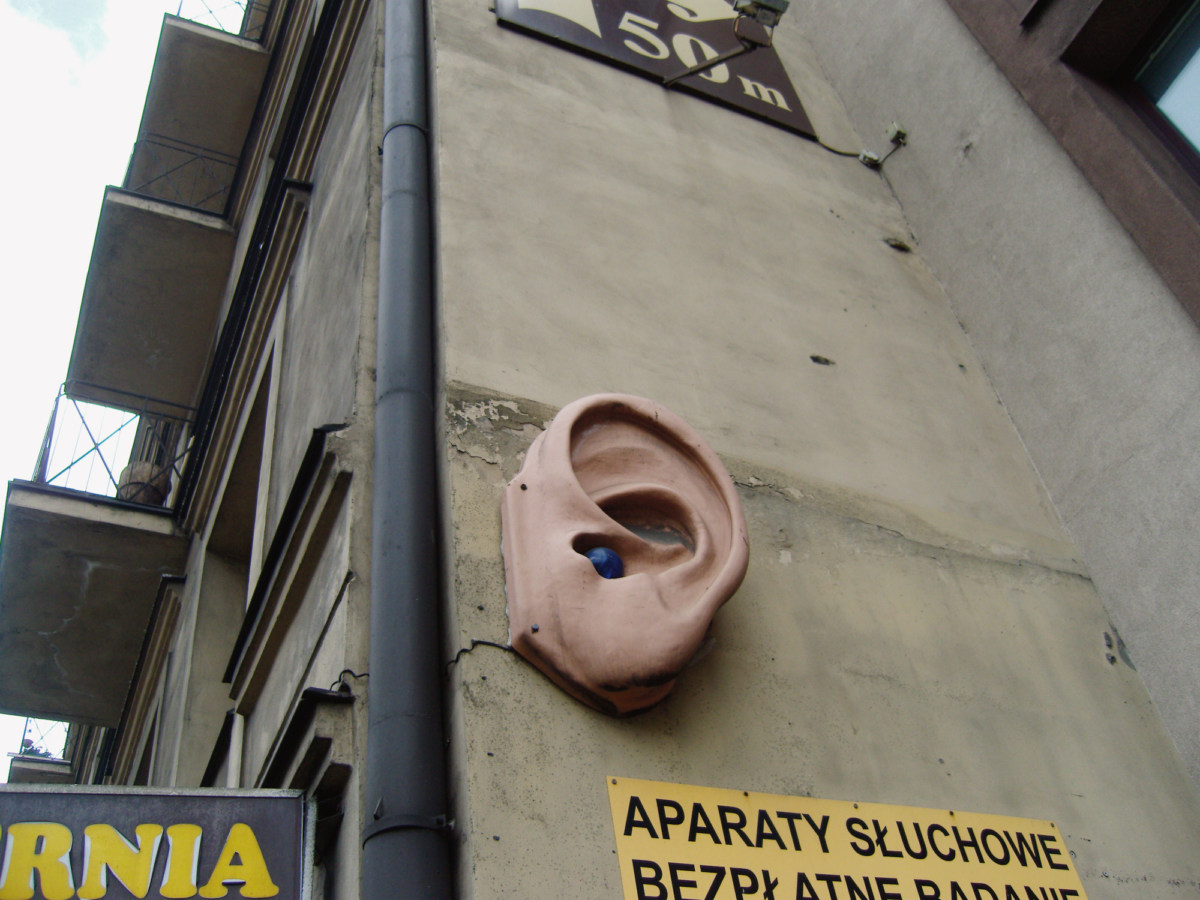 A color photograph of a sculpture of an ear, mounted on the exterior wall of a building