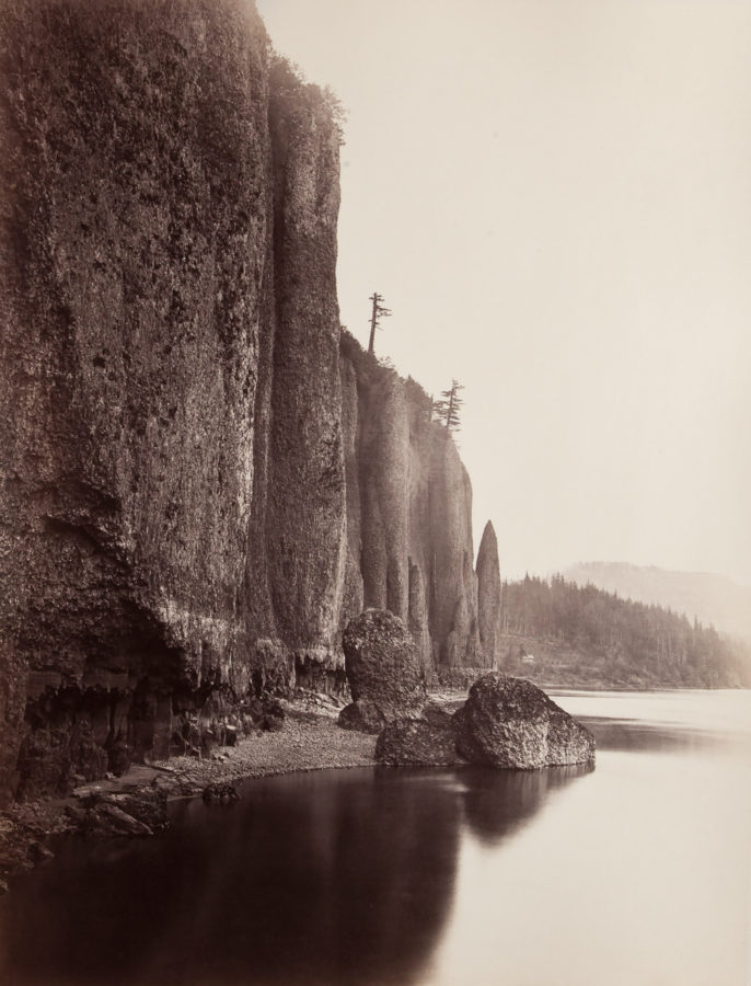 Ninteteenth century photograph of a sheer cliff side at the edge of a river