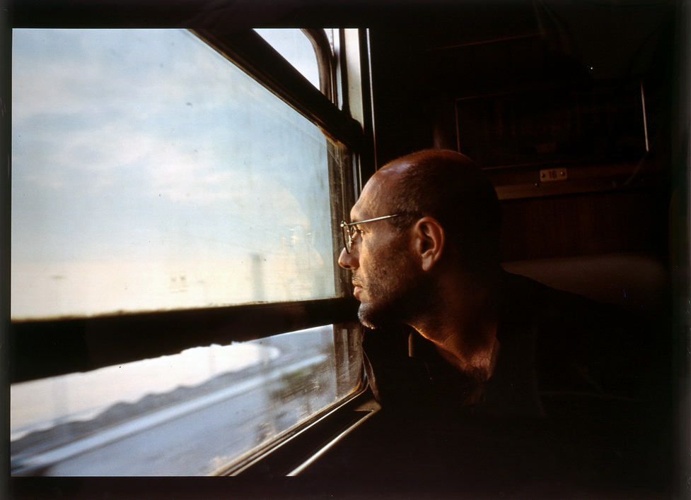 Color photograph of a man looking out a train window