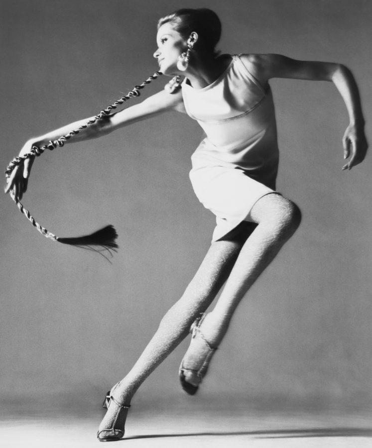 Black and white photograph of a woman dancing in front of a grey background.