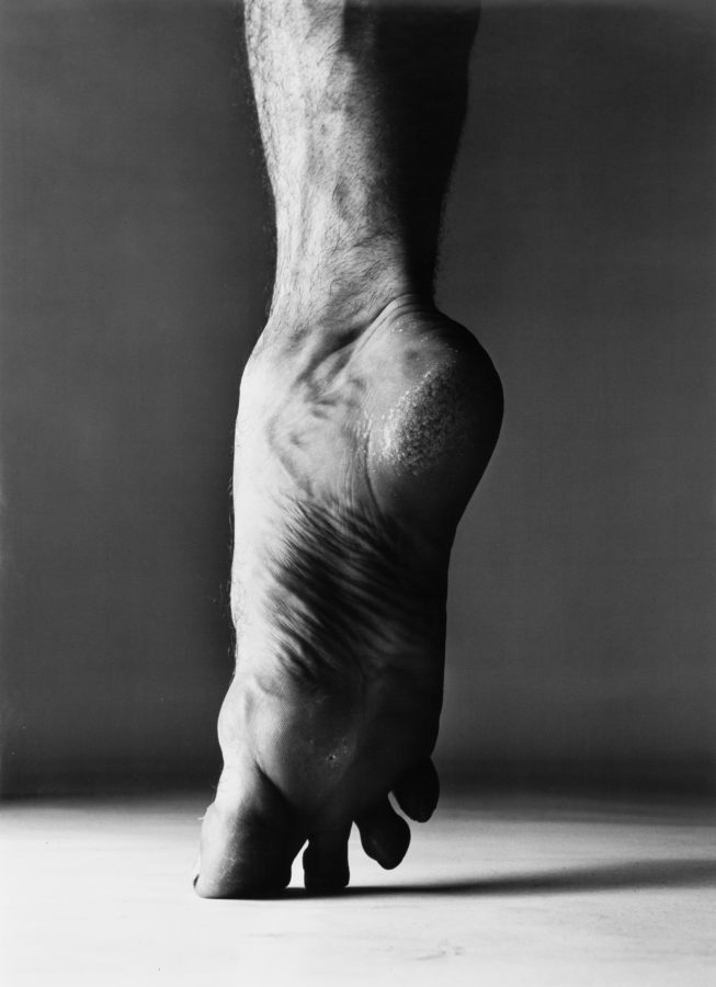 Black-and-white photograph of a bare foot standing on tiptoe