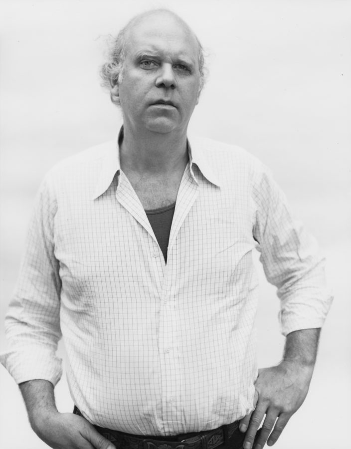 Black and white photograph of a man looking directly at camera against a white background