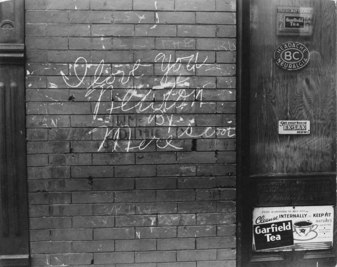 Black-and-white photograph of a brick wall with chalk grafitti that readsy, I love you Newton by Mere Scoot