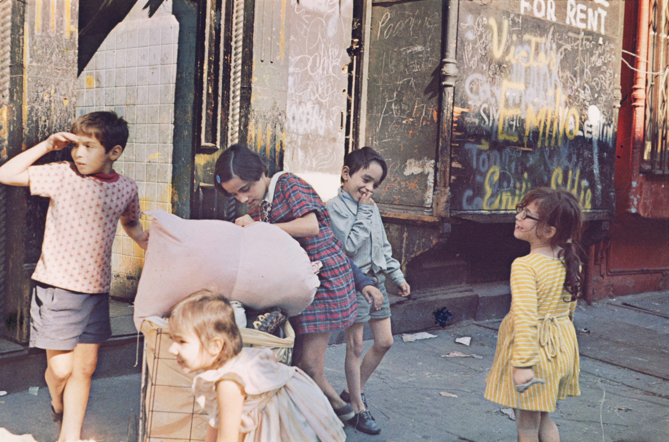 Color photograph of five children playing on the sidewalk.