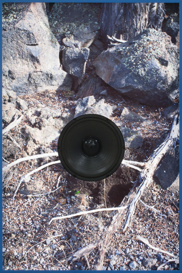 Color photograph of rocky earth cut around a black speaker