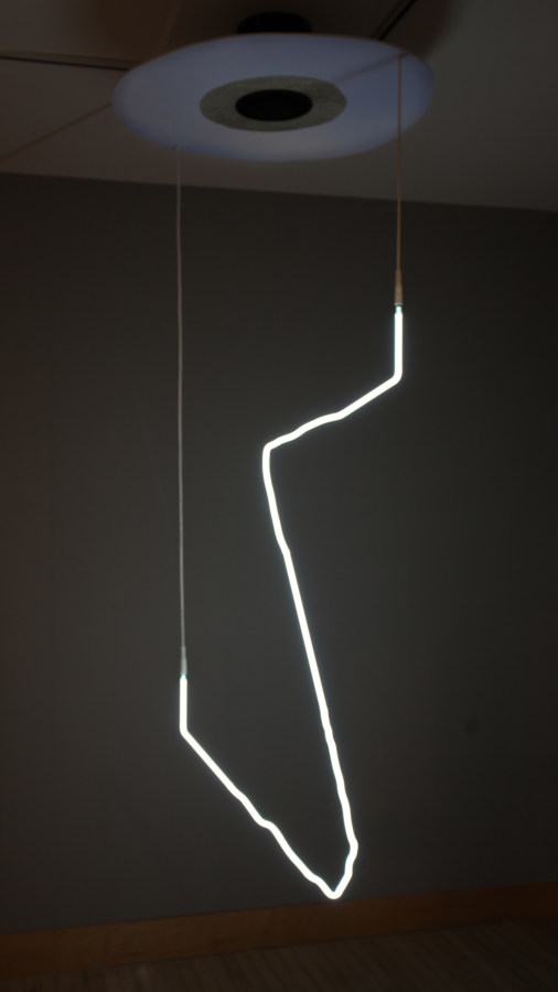 Bent white neon light hanging from a ceiling