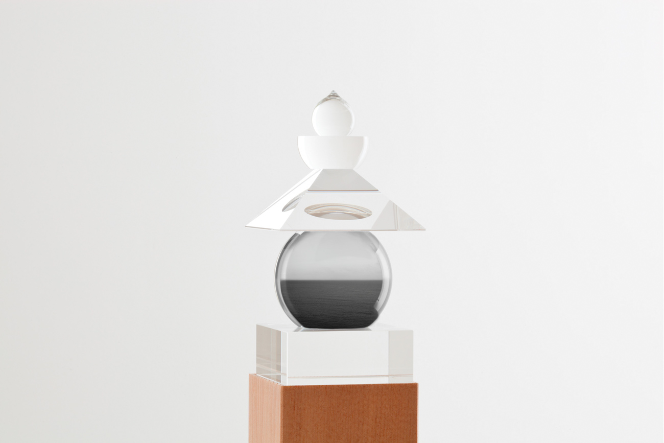 Glass sculpture of stacked geometric shapes with a black-and-white photo of a seascape inserted in the central orb