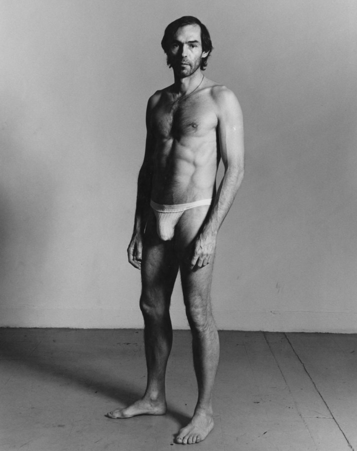 Black-and-white vertical photograph of a standing man wearing a jock strap.