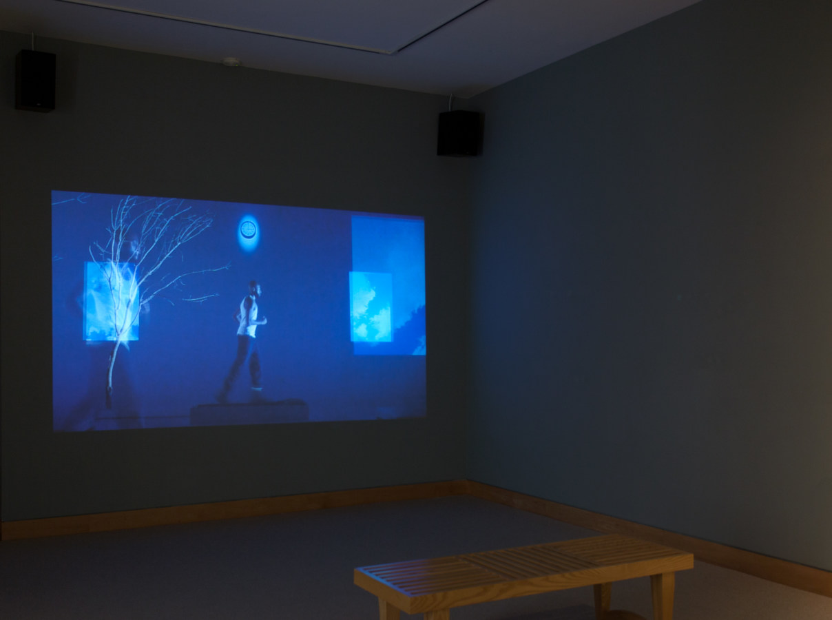 Installation photograph of a video projected on the wall of a darkened gallery