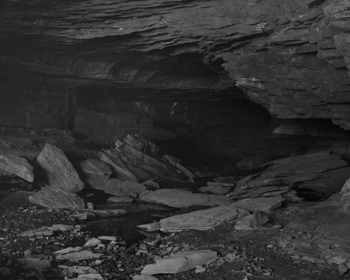 Black and white photograph of the interior of a rocky cave