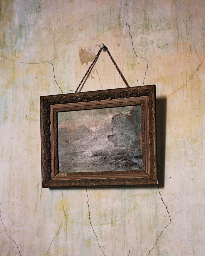A photograph of a painting against a faded, cracked wall.
