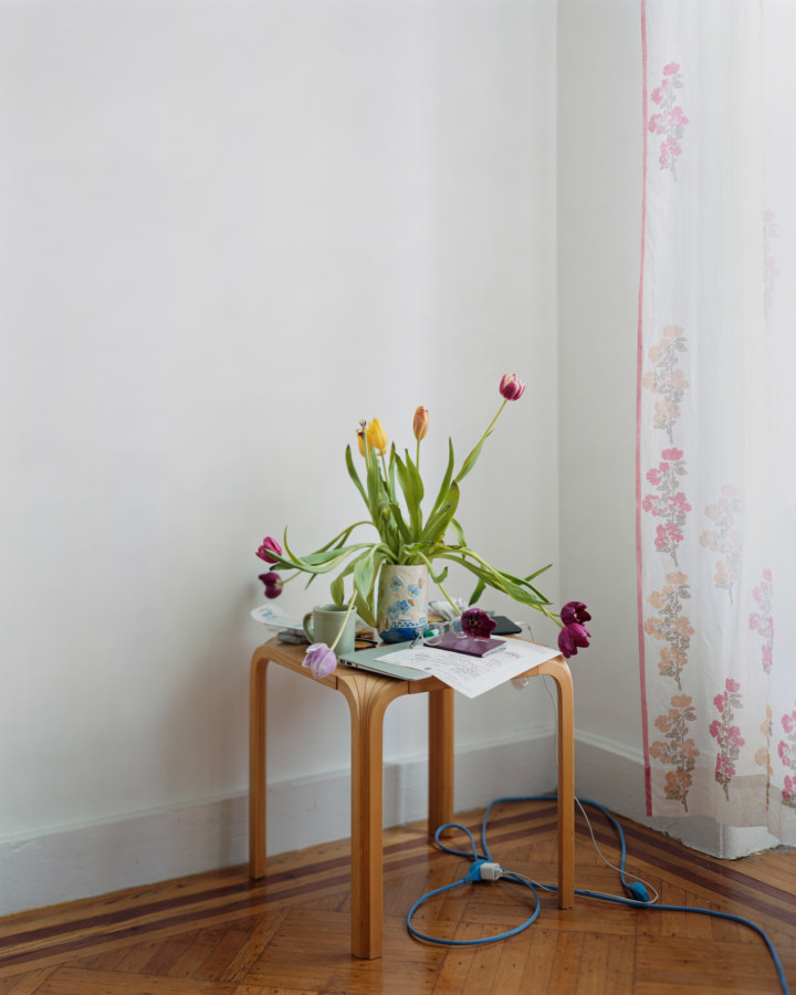 Color photograph of a vase of tulips on an end table in the corner of a room