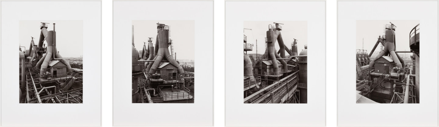 Four framed black and white photographs showing a factory building from various angles.