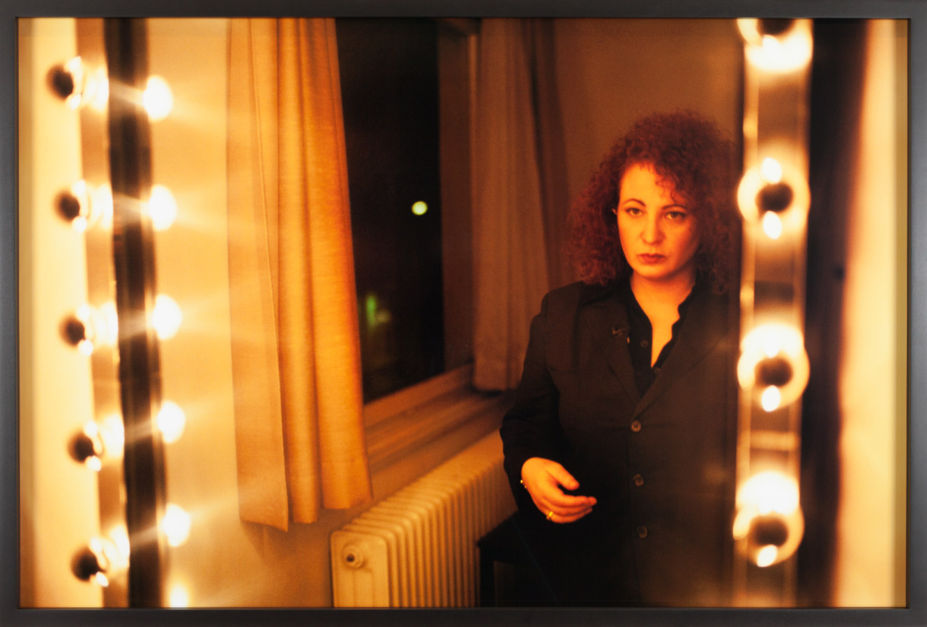 Color photograph of a woman looking at her reflection in a vanity mirror