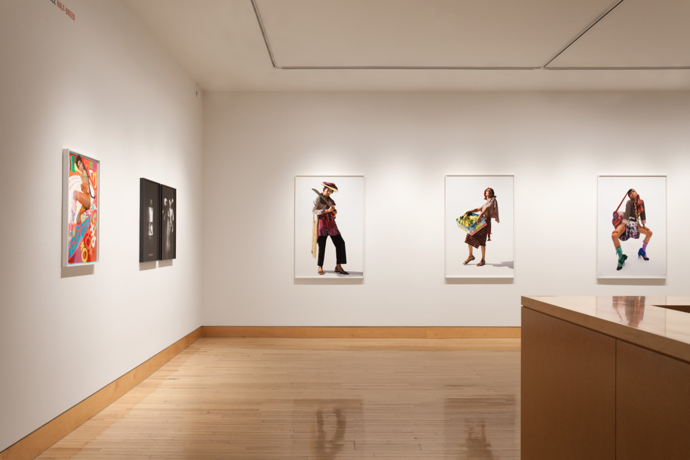 Color image of gallery entryway exhibiting framed color photographs on white walls