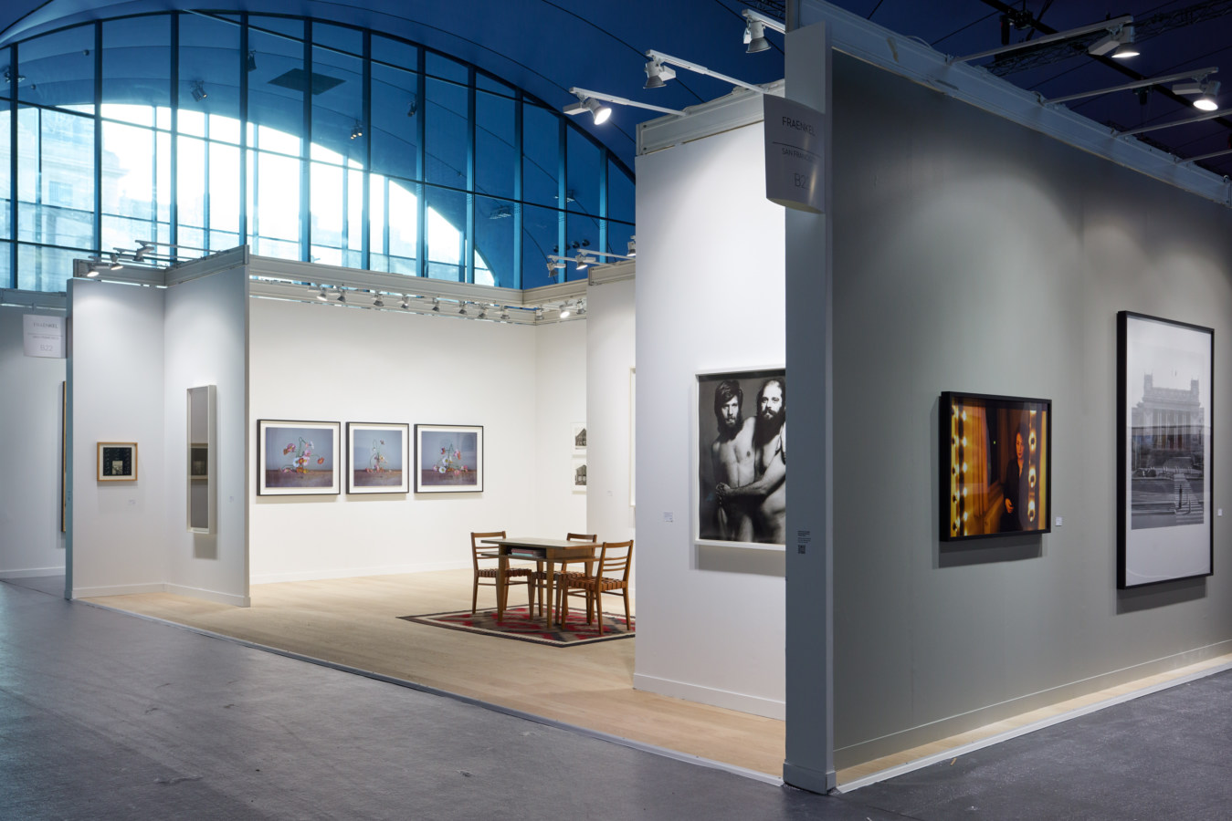 Color image of various artworks installed in an art fair booth on white and grey walls