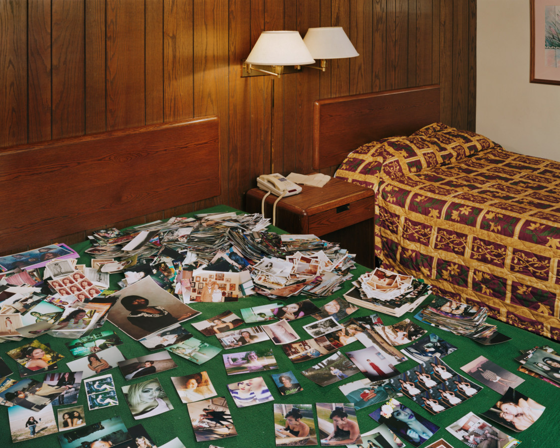 Color photograph of a hotel bed covered in small color photographs