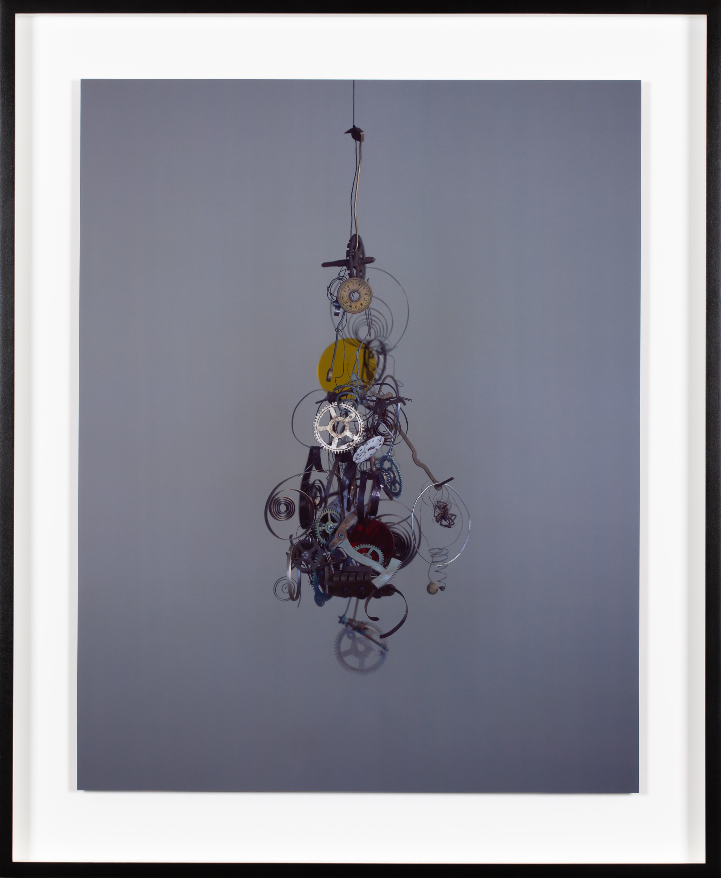 Framed color photograph of a cluster of clock gears suspended on a wire
