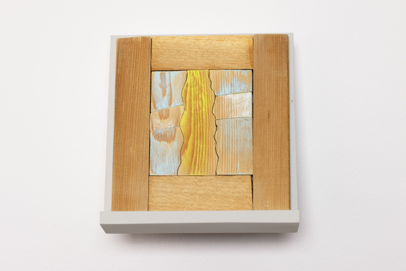 Color photograph of woodblock depicting yellow, white, and blue washed forms on white stand
