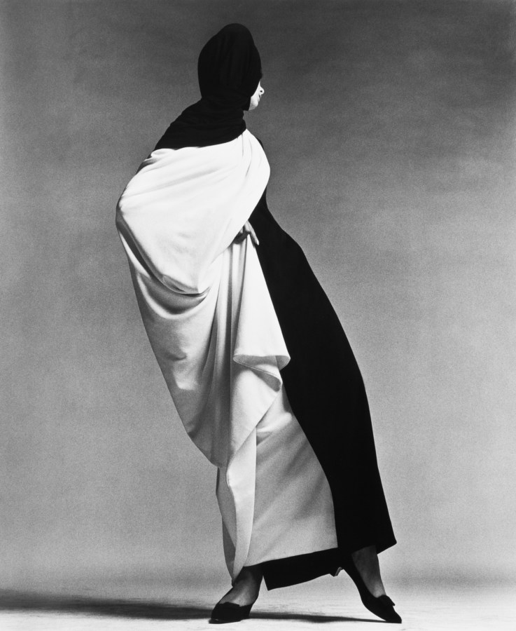 Black and white photograph of a woman standing wrapped in a black and white gown