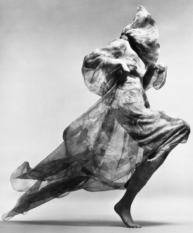 Black and white photograph of a person in mid-step in a sheer gown