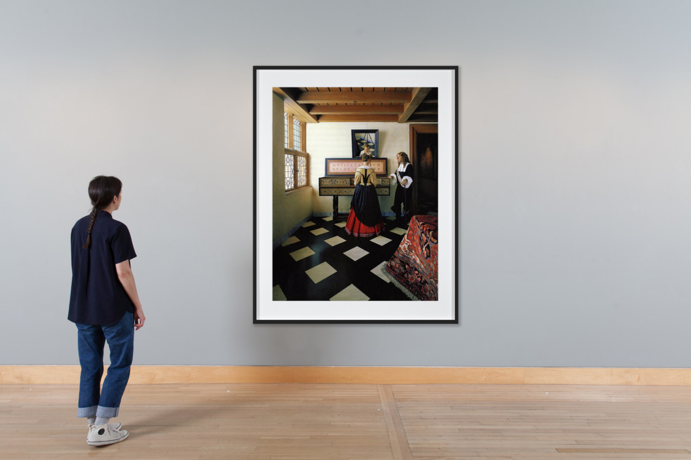 Installation view of a framed color photograph of a European Baroque scene of two people standing at a harpsichord.