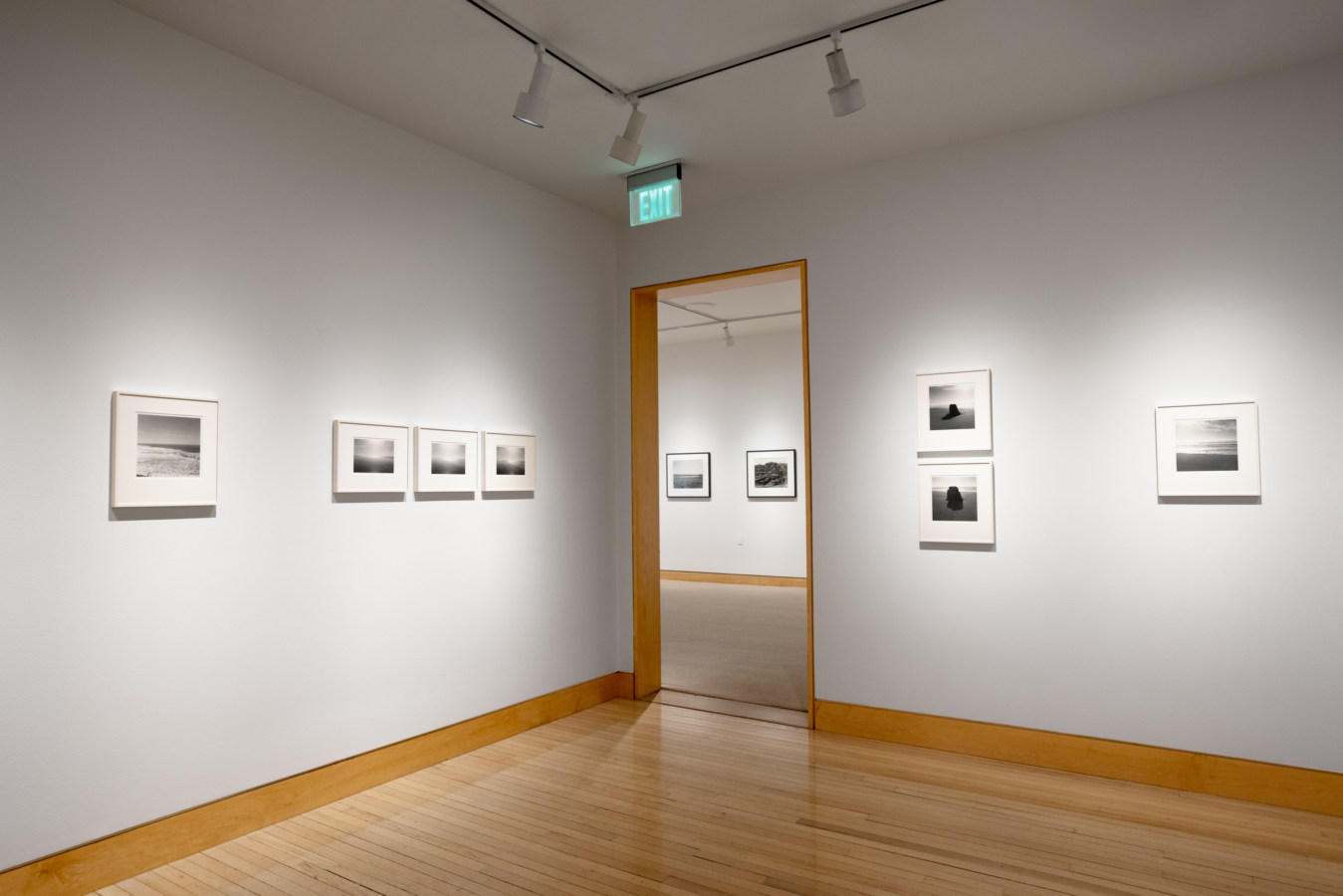 Color image of black and white photographs framed on white gallery walls