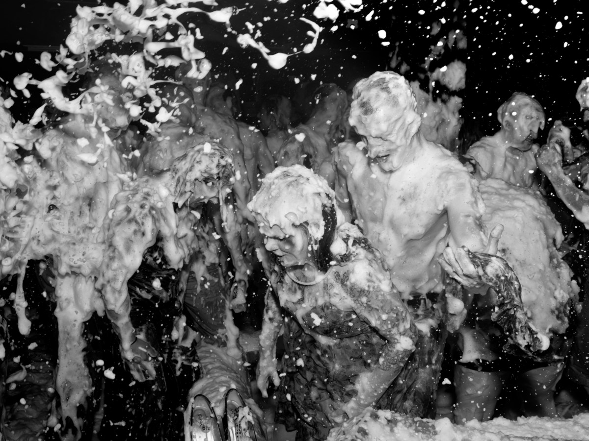 Black and white photograph of a group of individuals dancing while covered in foam