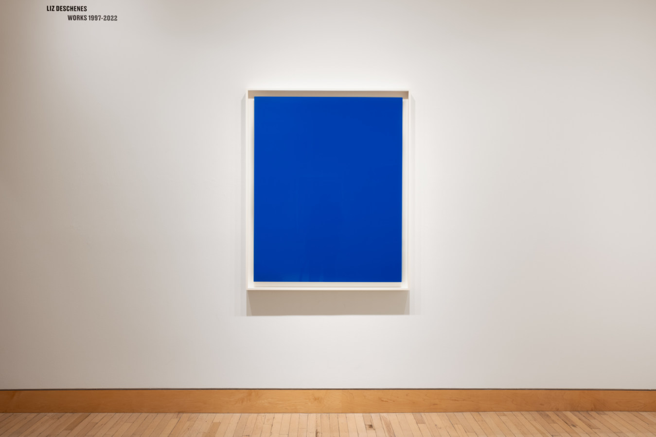 Color image of blue photogram framed in white on white gallery wall