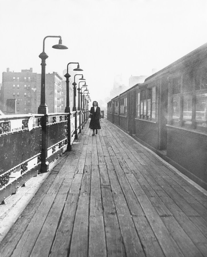 Black and white photograph of a subway platform with women walking