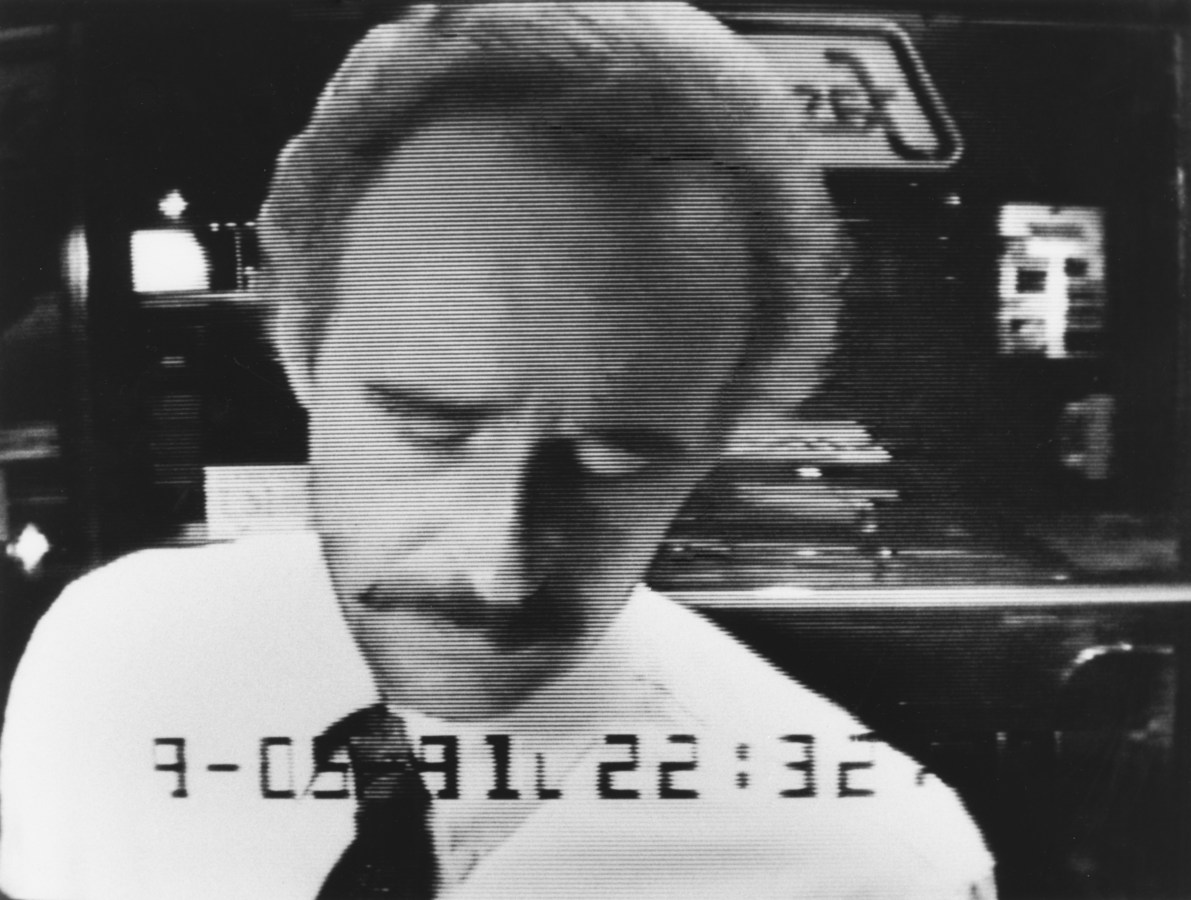 Black and white photograph of mustachioed man at ATM machine