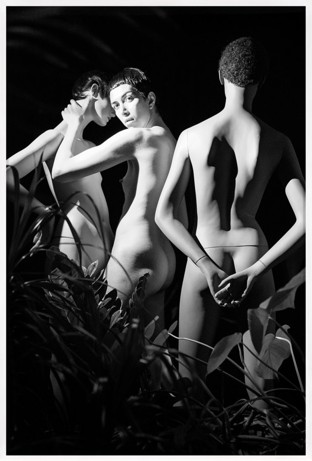 Black and white photograph of three nude bodies amongst greenery