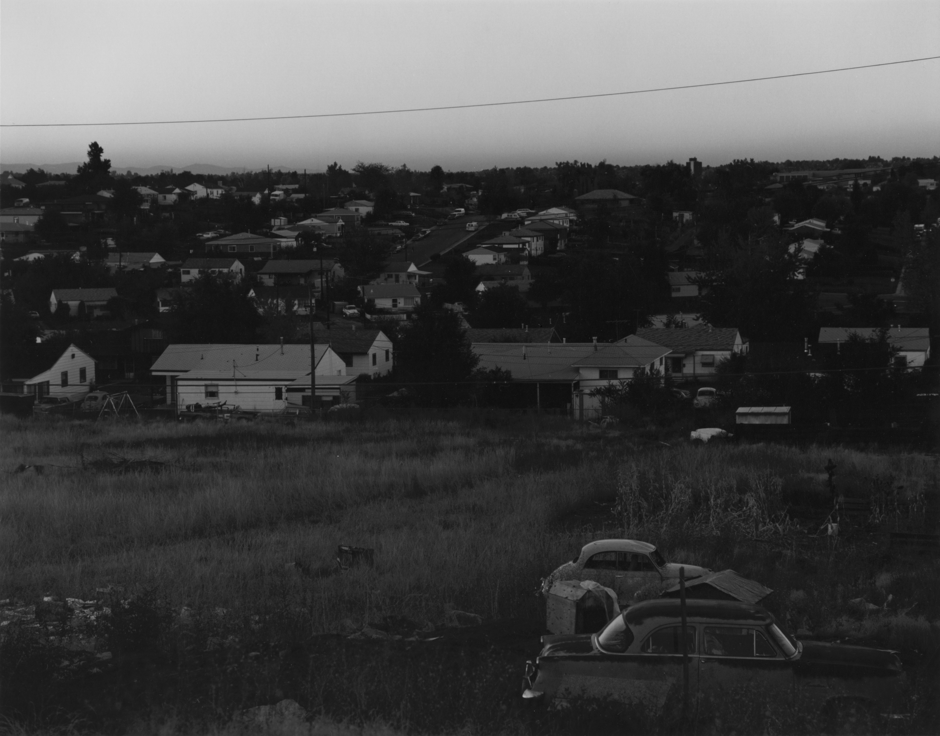 Black and white photograph of empty field and residential neighborhood
