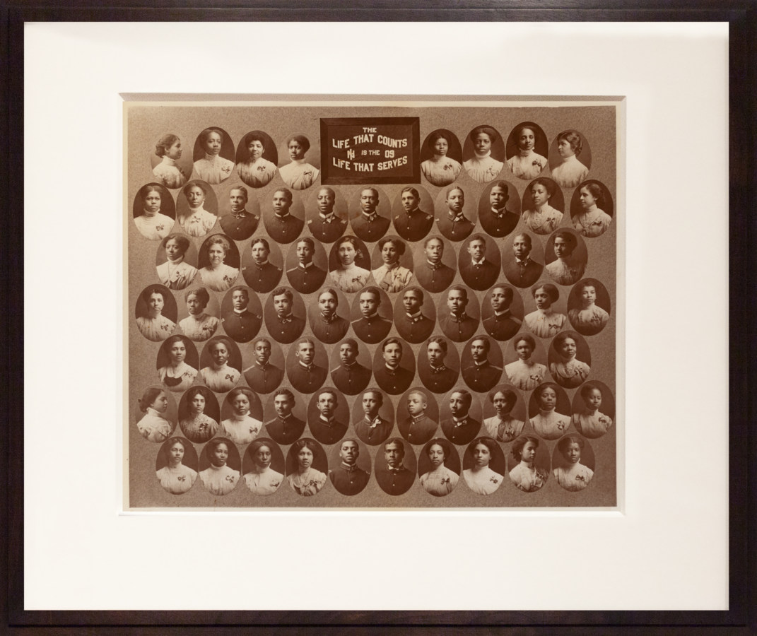 Color image of color photograph depicting a graduating class framed in dark wood