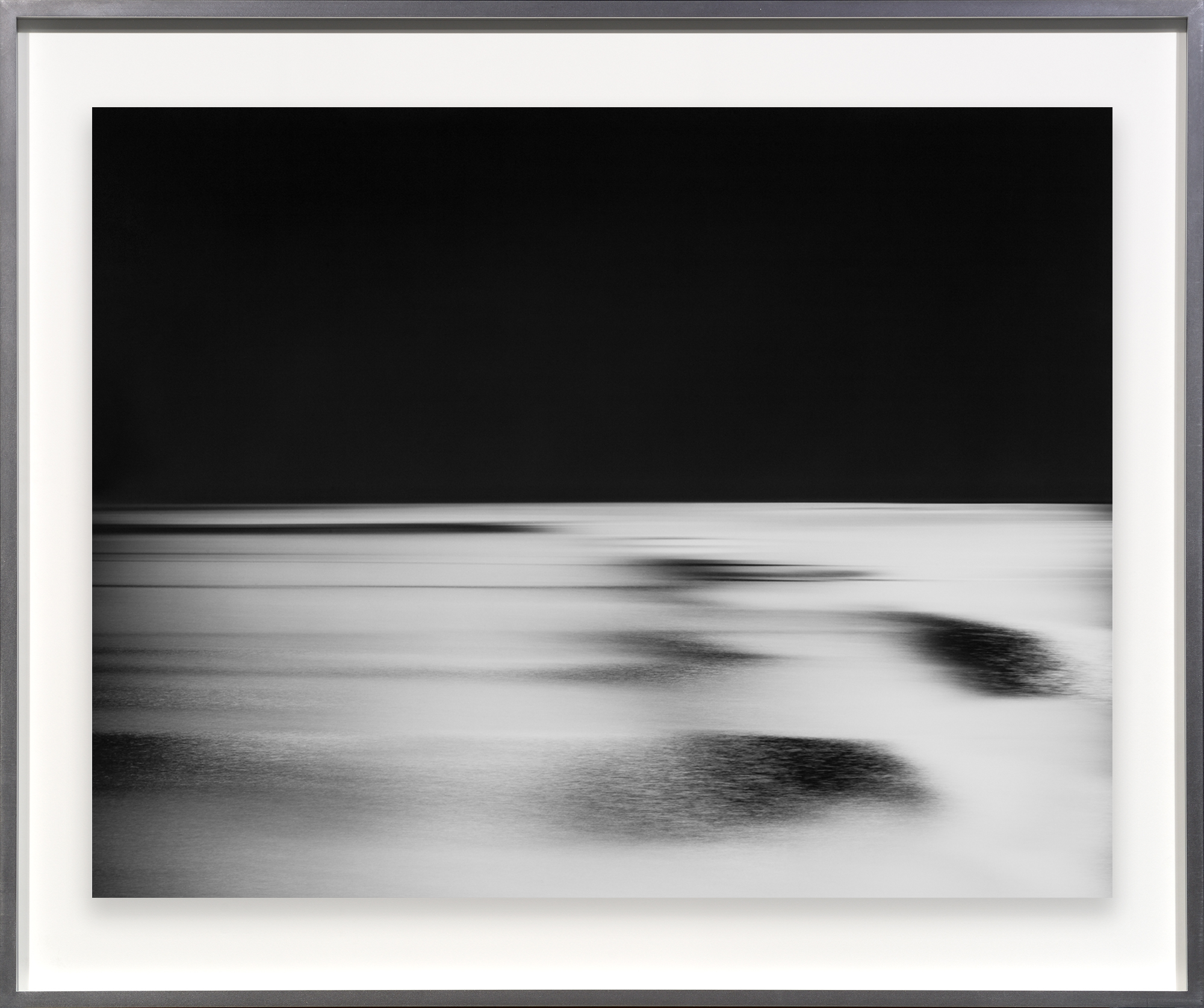 Color image of a black and white photograph of a time lapse of a river along the horizon framed in metal