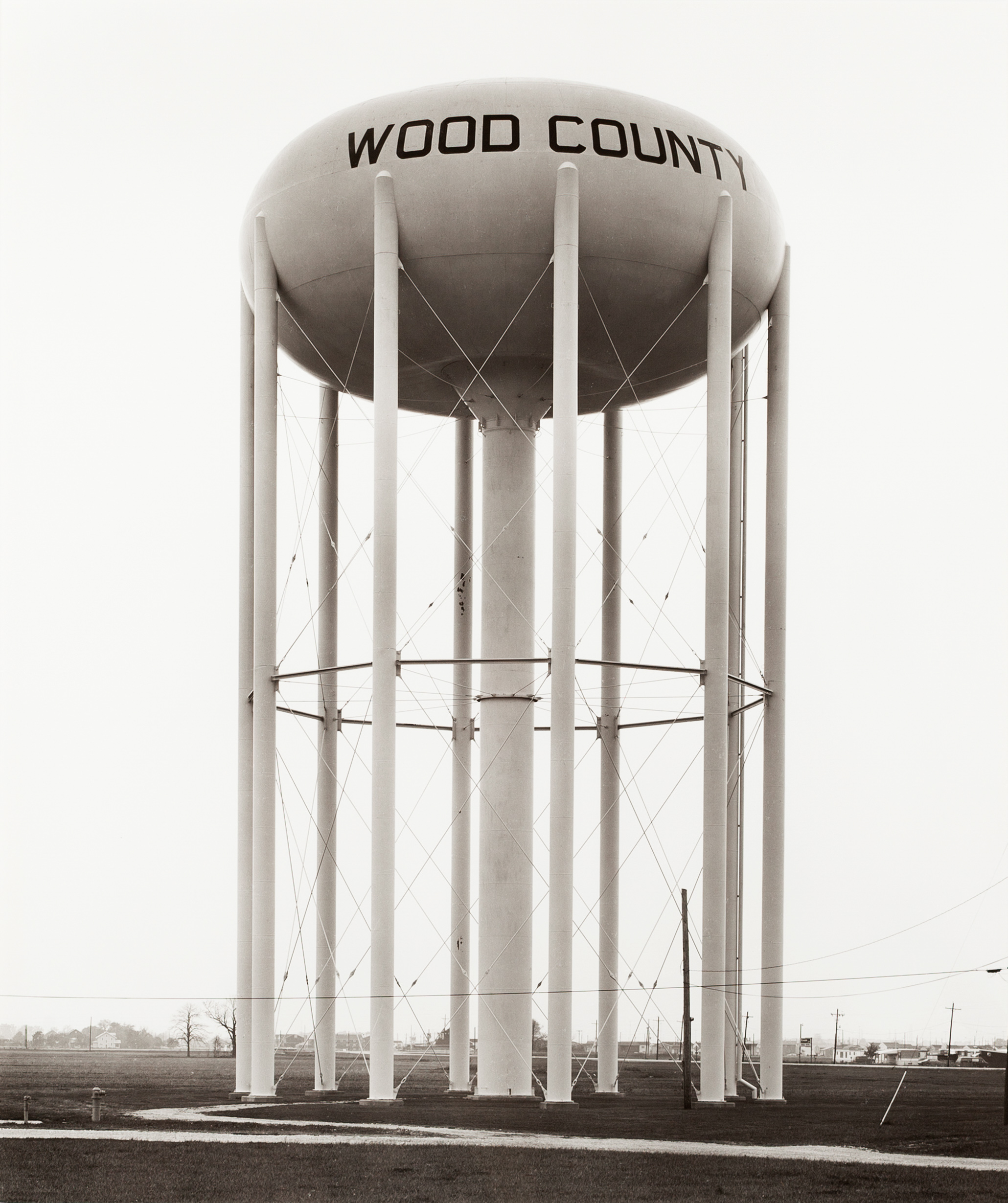 Black and white photograph of a water tower in a grass field