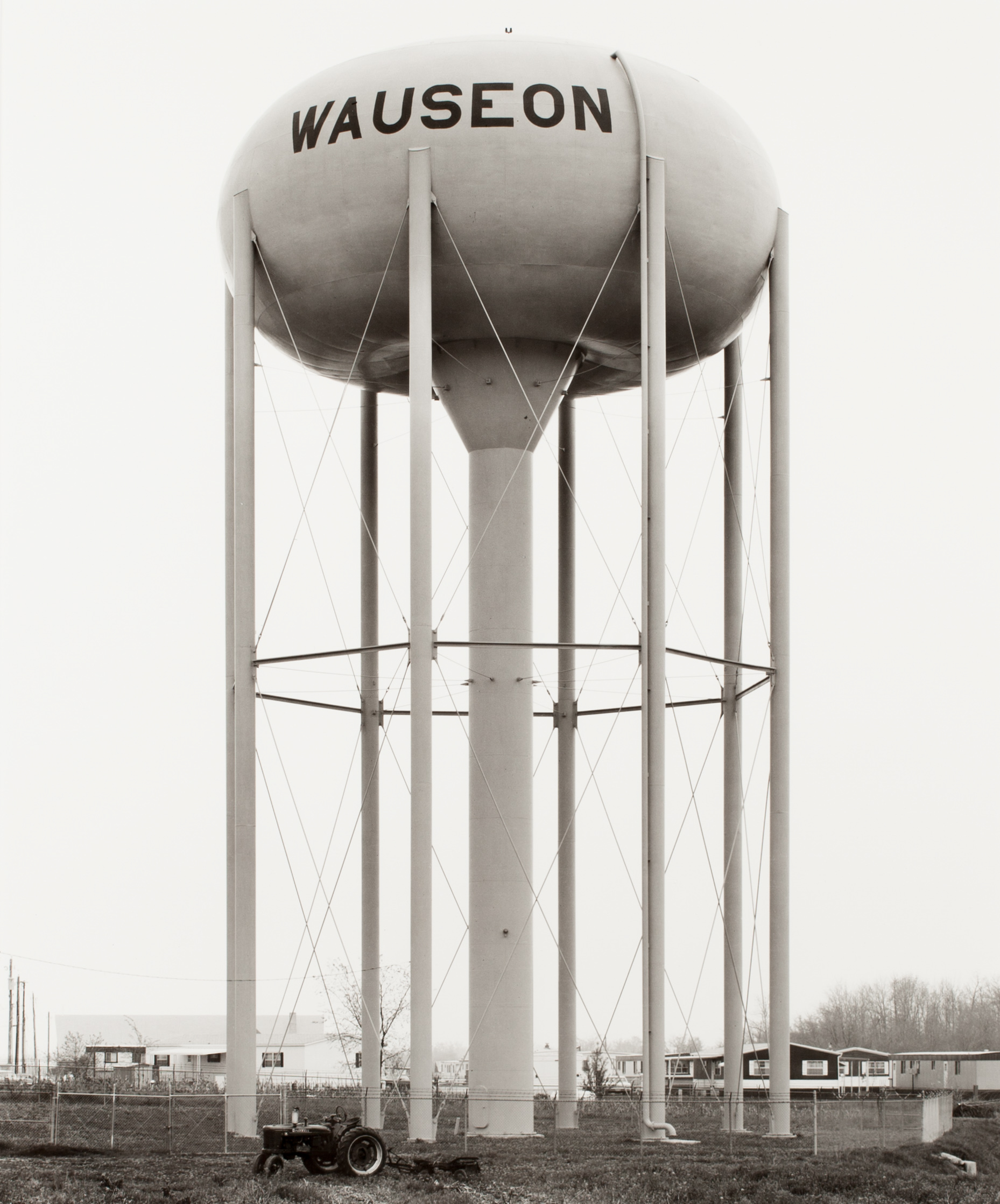 Black and white photograph of a water tower amongst residential homes