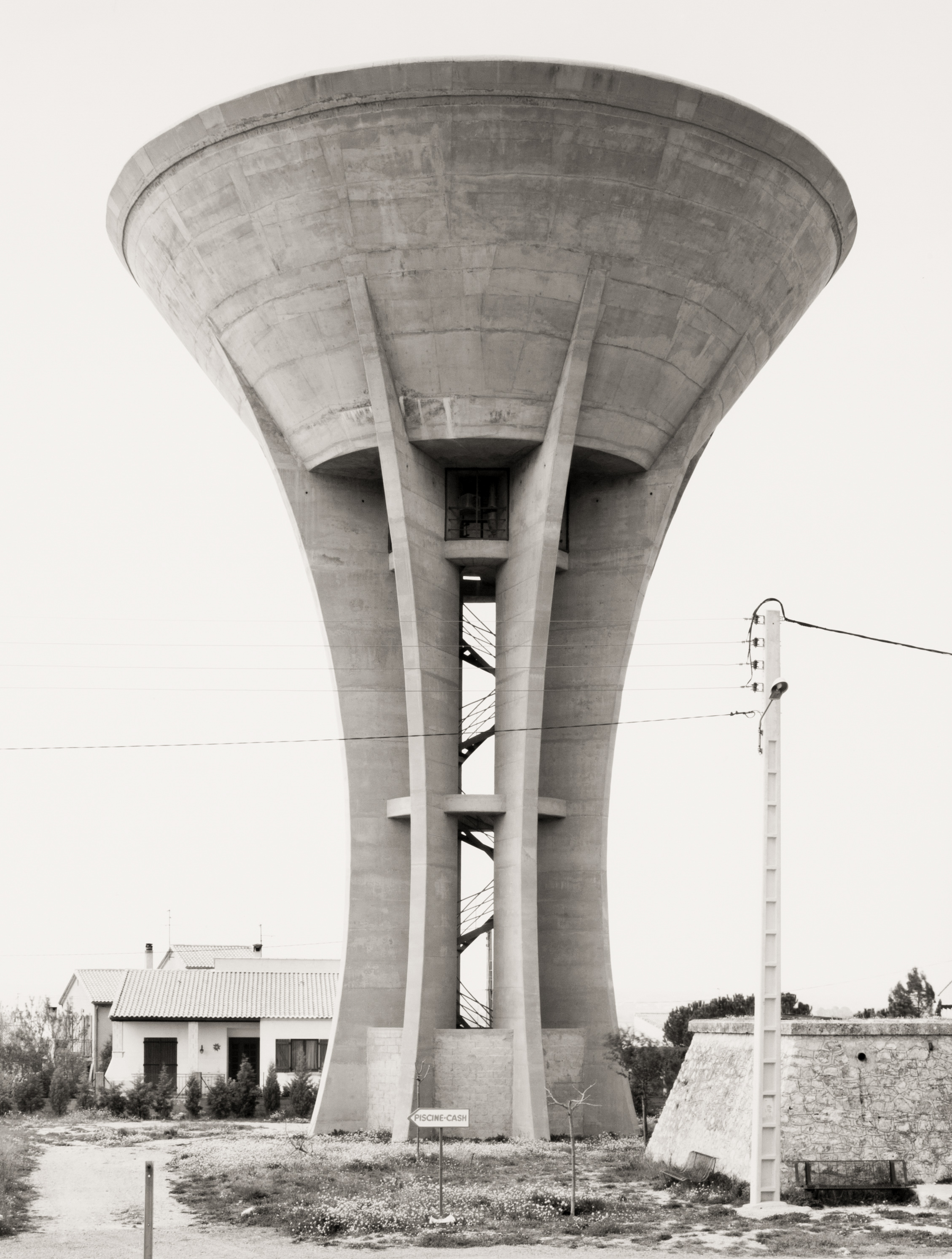 Black and white photograph of a water tower near electrical power lines
