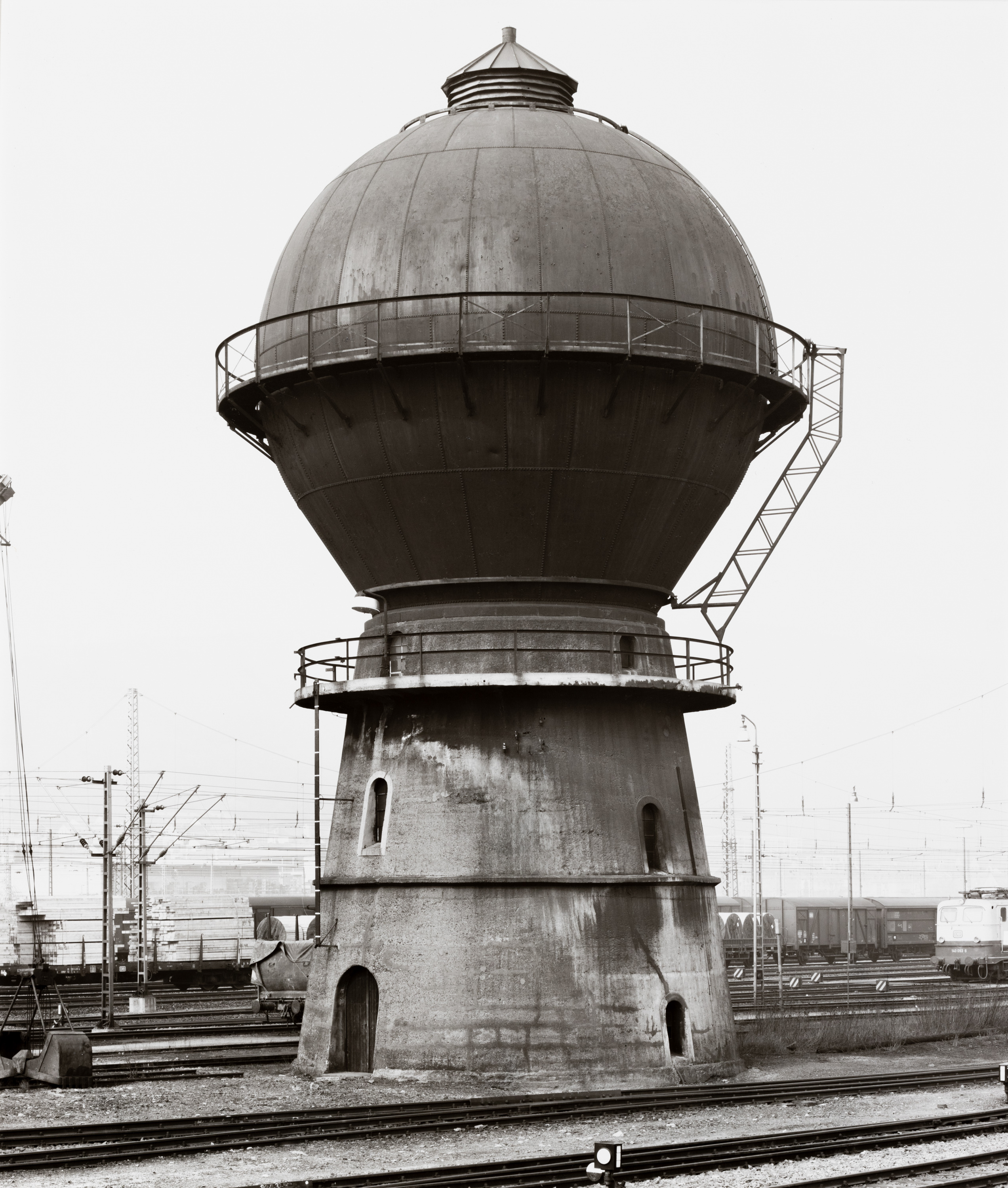 Black and white photograph of a water tower amongst railroad tracks