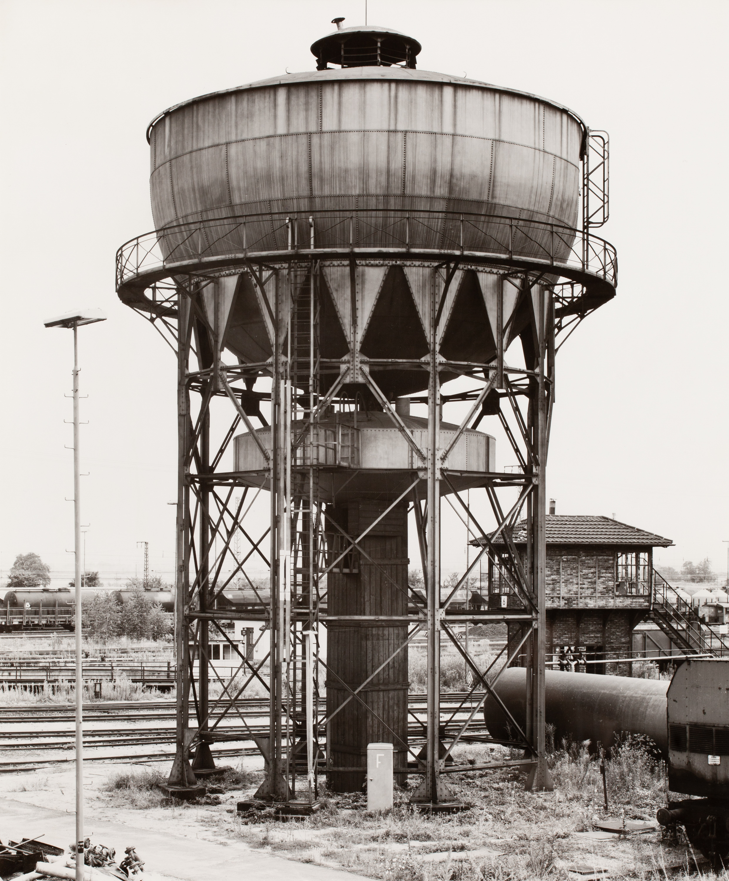 Black and white photograph of a water tower near railroad tracks