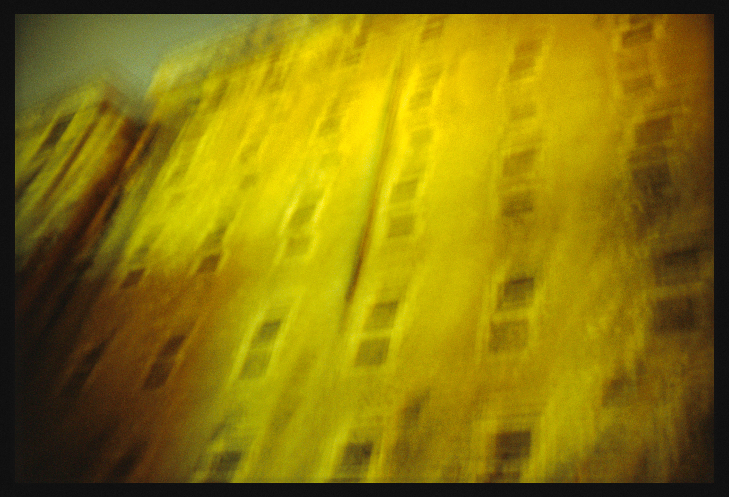 Color photograph of the facade of a building at night with motion blur framed in black